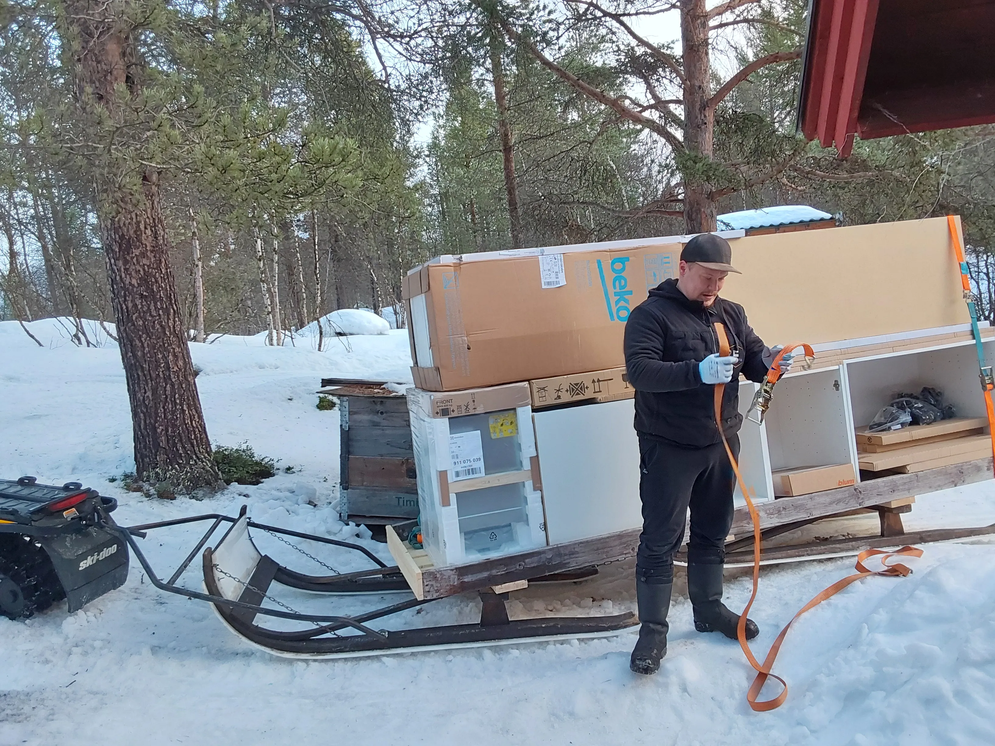 Kjøkkenskap og hvitevarer surret fast på slede bak snøscooter